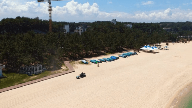 View of a sandy beach with a quad bike passing by