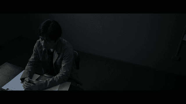 Man sitting at table with documents in dark room