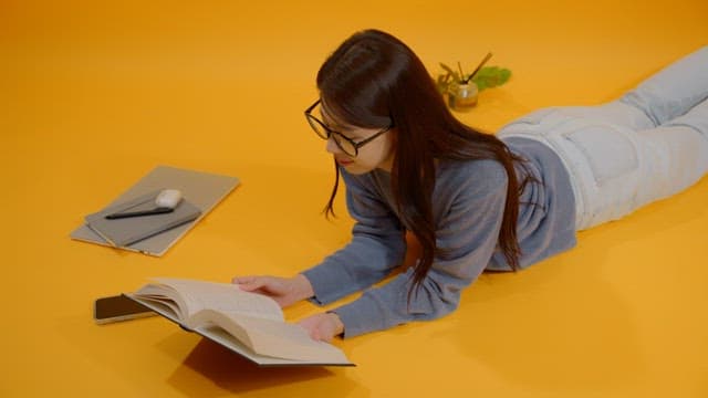 Woman reading a book while lying on her stomach in a bright room