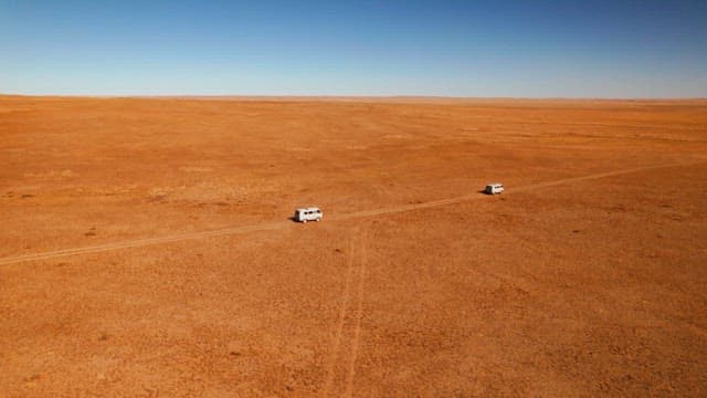 Vans traversing a vast, arid landscape