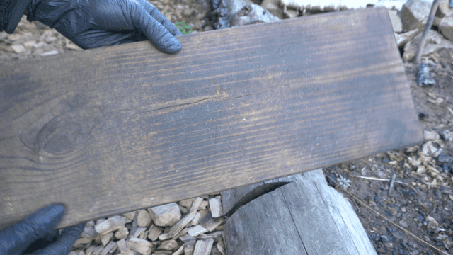 야외 작업장에서 태운 나무 판자를 검수하는 작업자