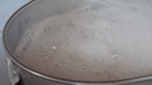 Foamy bone broth cooking in large pot