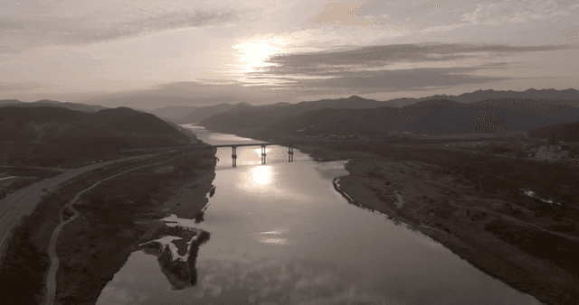 A serene river with a bridge at sunset
