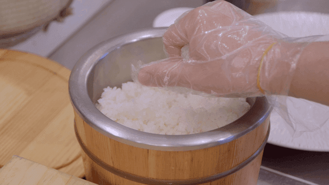 Chef shaping rice by hand in wooden bowl