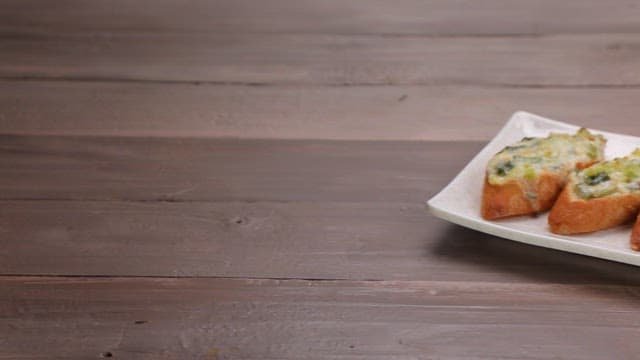 접시 위에 먹음직스러운 파가 올라간 바삭한 바게트