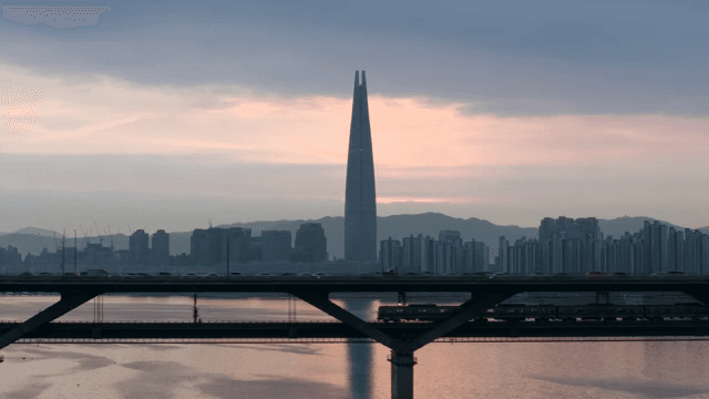 Train running through a city at dusk with high-rise towers