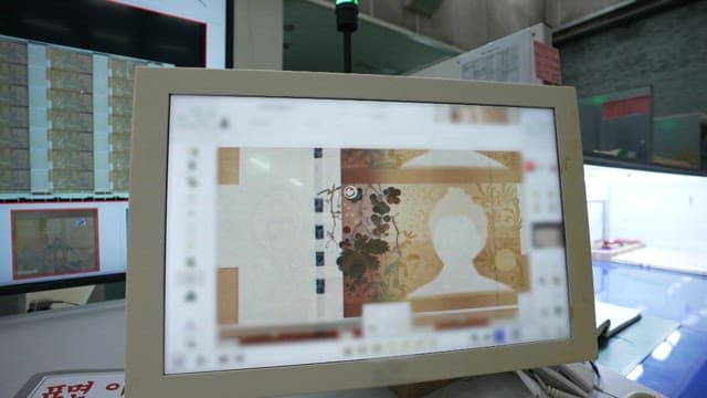 Analyzing a print of a 50,000 won note in a factory setting