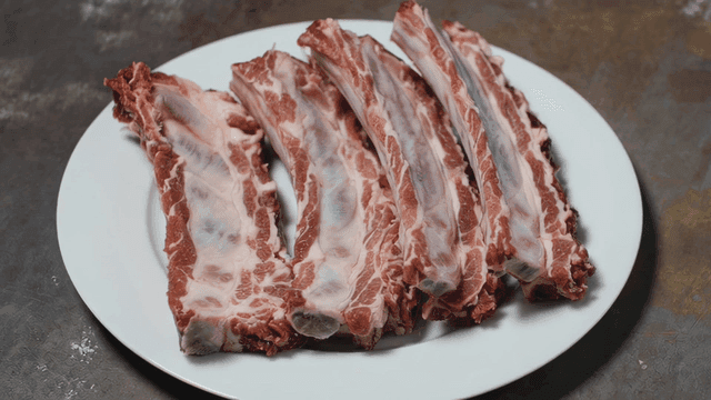 Raw ribs neatly arranged on a white plate