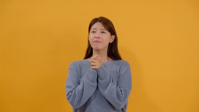 희망적인 표정으로 손을 모아 기도하는 여성