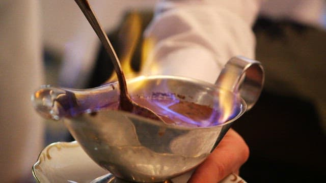 Chef pouring chocolate sauce over crepes