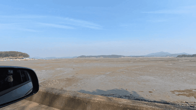 Drive along wide mudflat with mountains visible in distance