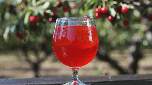 Glass of cherry juice on table