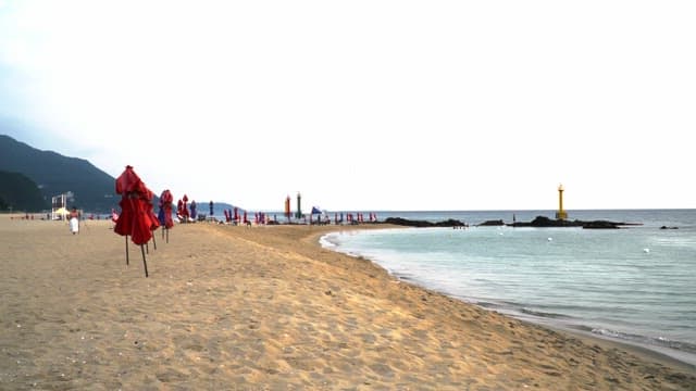 Sandy beach with red parasol and a lighthouse