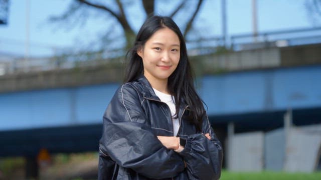 미소를 지으며 팔짱을 끼고 서 있는 여성