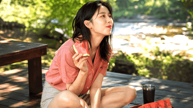 강가에서 수박을 먹는 여성