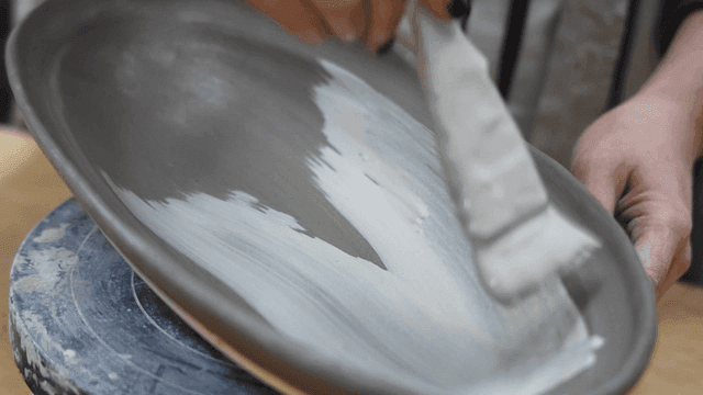 Applying glaze to a pottery piece