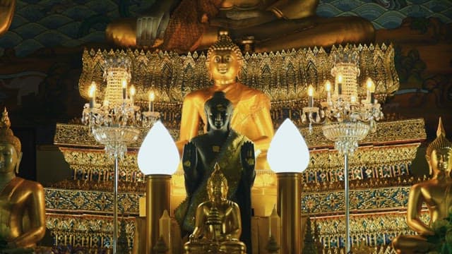 Multiple Buddha statues in a richly decorated temple.