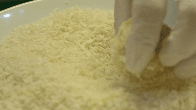 Gloved hands dipping into breadcrumbs and dough