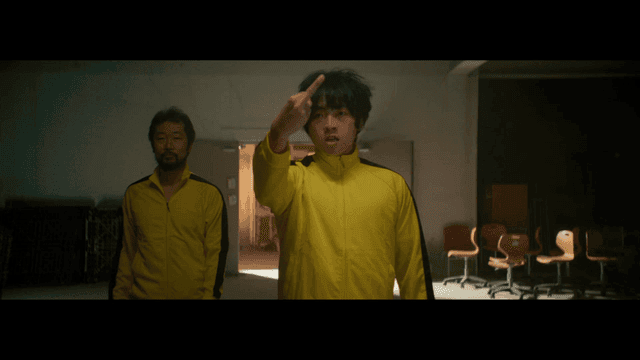 노란 트레이닝복을 입고 손가락 욕을 하는 남자