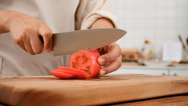 Cutting fresh tomatoes on wooden cutting board