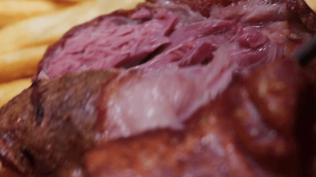 Juicy pork being sliced with fries