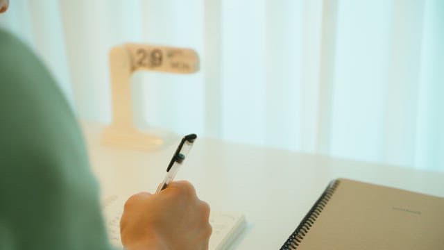 Person taking notes in a notebook at a desk