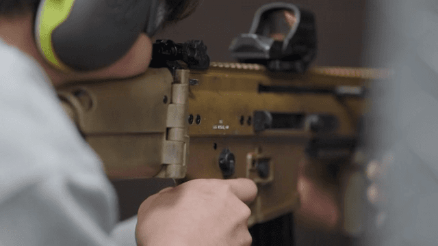 Person aiming a rifle at a shooting range
