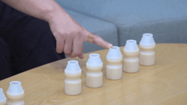 Hand pointing at yogurt bottles on a table