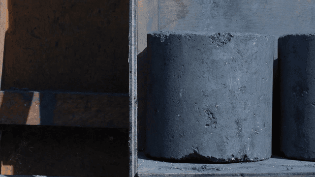 Gloved hand handling charcoal briquettes