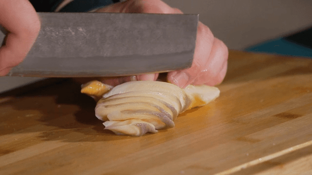 나무 도마 위에서 소라를 자르는 모습