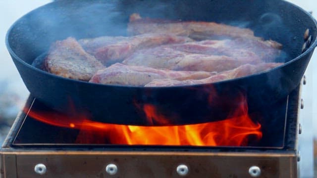 Fresh lamb being cooked in a frying pan on the portable stove