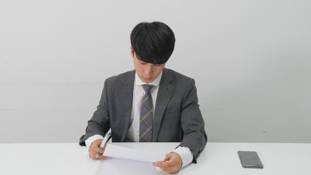 Man in a suit diligently reviewing and signing documents in a bright office