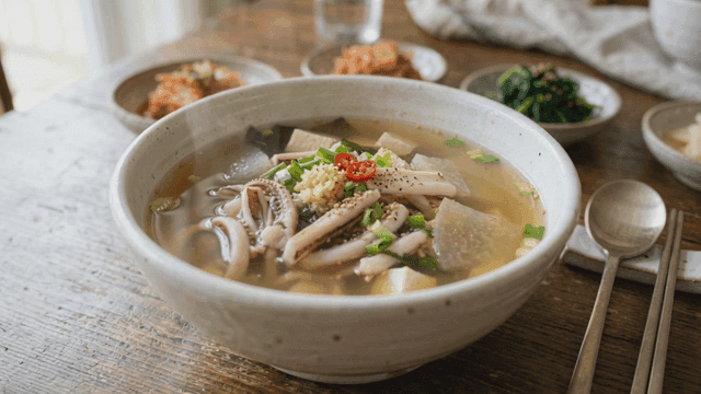 Bowl of squid soup with side dishes.