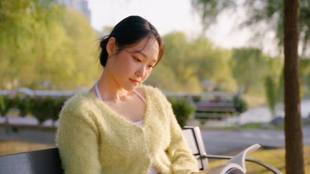 Woman reading a book on a park bench