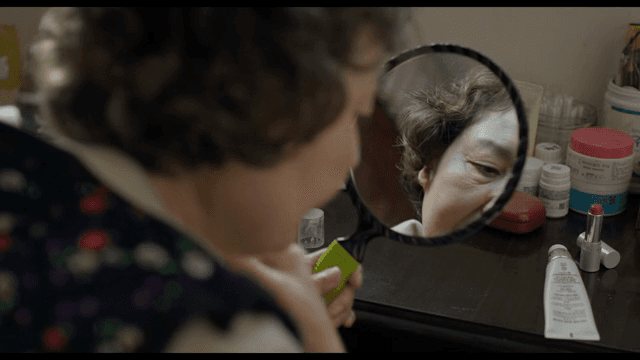 거울을 보며 립스틱을 바르는 노인 여성