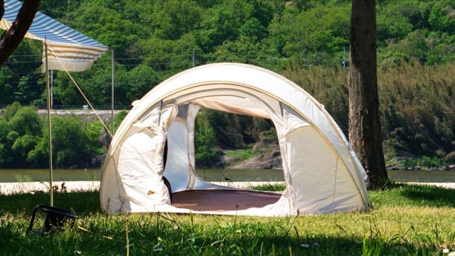 Camping tent set up in a grassy area on a sunny day