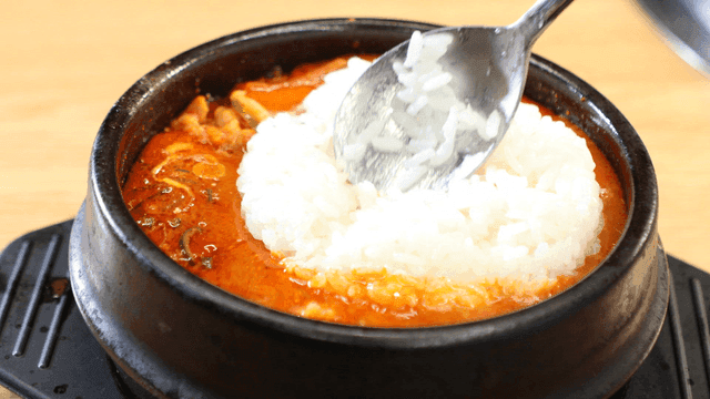 White rice added to soybean paste stew in earthenware pot
