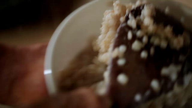 Freshly cooked barley rice being placed in a rice bowl