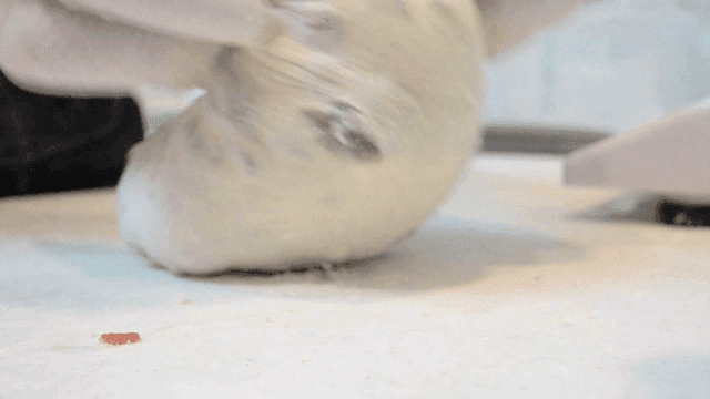 Baker kneading dough with dried cranberries and nuts