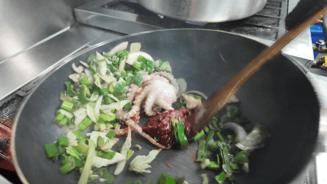 Octopus and vegetables stir-frying in a pan