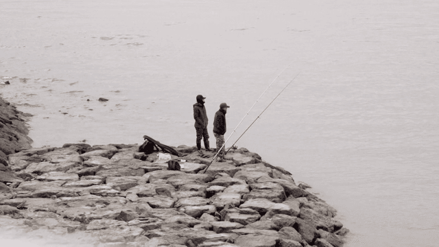 바위 해안에서 낚시하는 두 사람