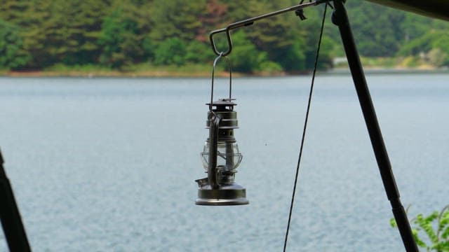 Setting up a camping lantern on the lakeside