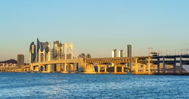 From day to night view of a bustling port city Busan with tall skyscrapers and Gwangan Bridge