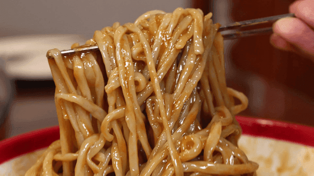 Jajangmyeon from red bowl lifted with chopsticks