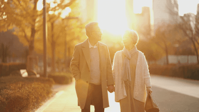Elderly couple walking down sunlit street