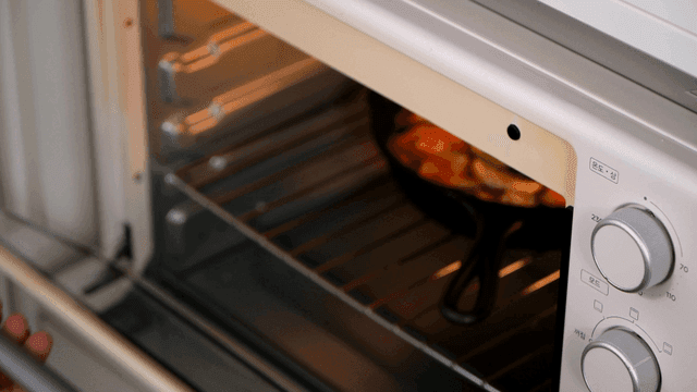 Hands taking out baked ratatouille from oven