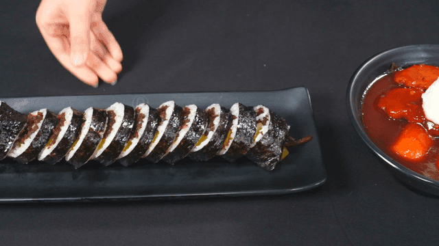 Kimbap and tteokbokki on a black table