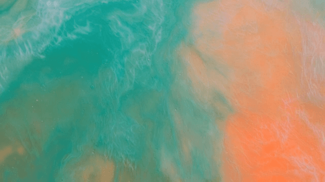 초록색과 주황색 액체가 혼합되는 추상적인 패턴