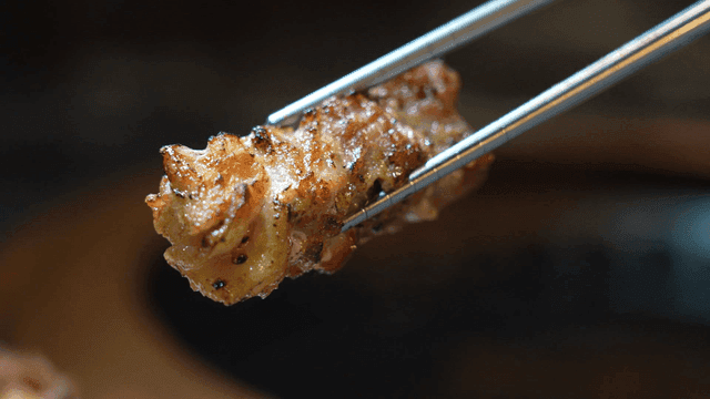 Grilled pork belly held with chopsticks