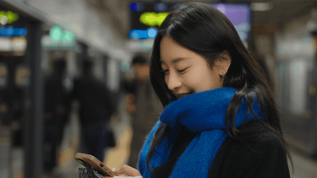 Woman smiling while using her cell phone at a subway station